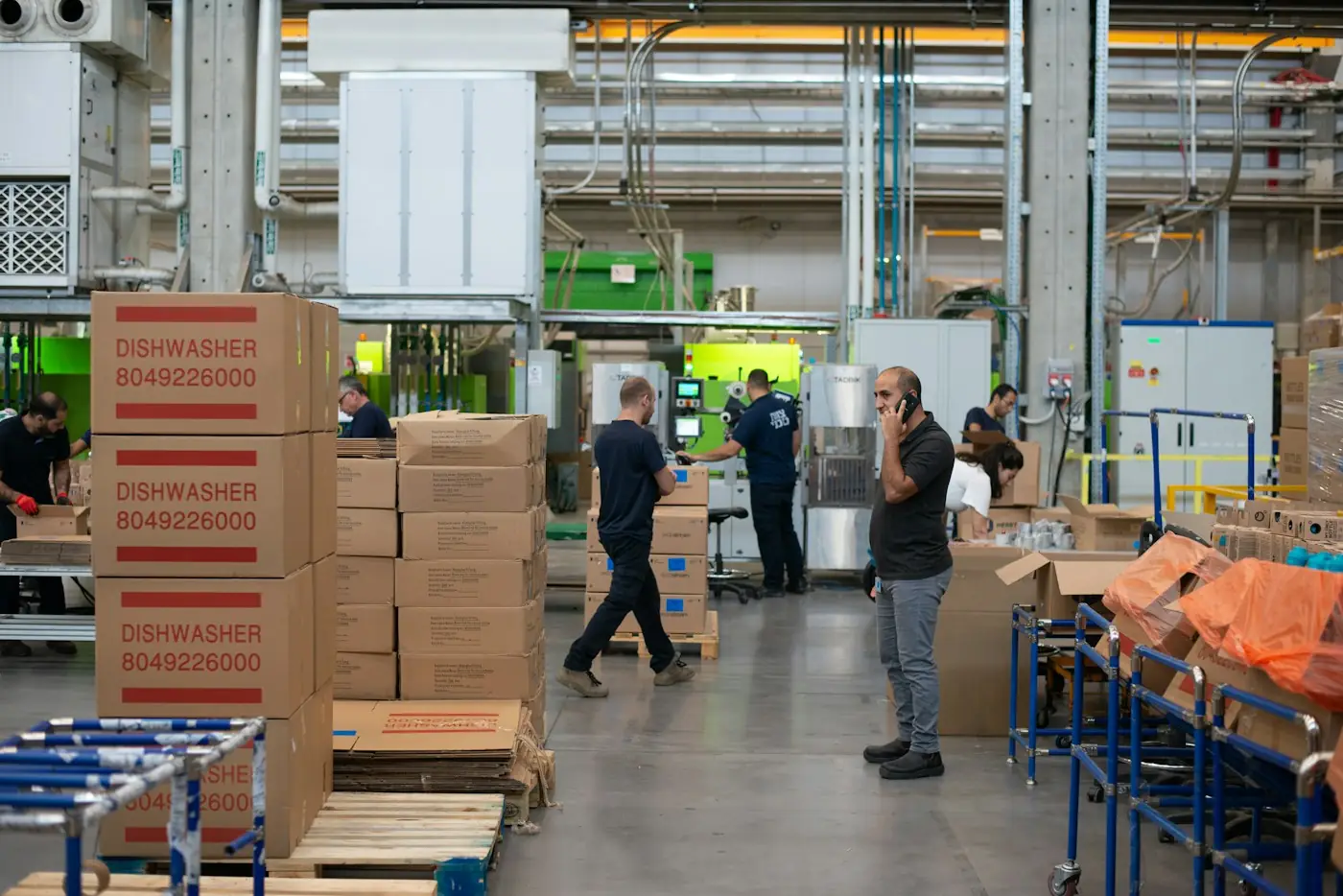 Worker beside stacked cartons in a packaging area